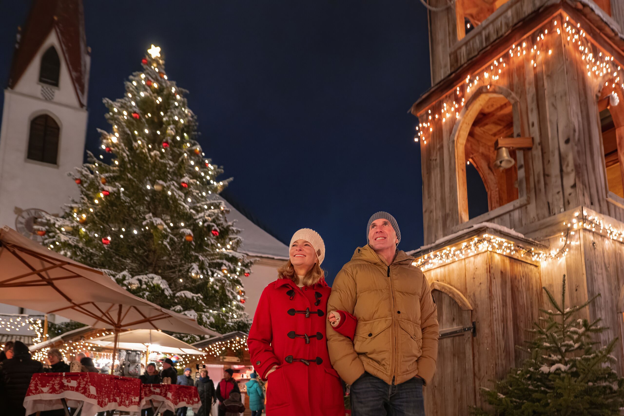 Weihnachtsmarkt Seefeld_Paar läuft über Markt neben Glockenturm